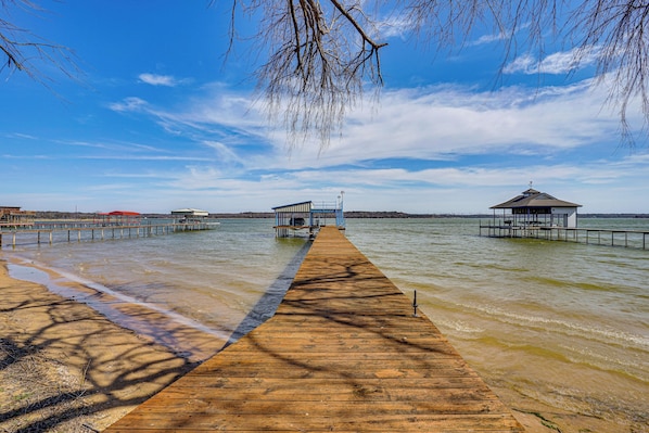 A wooden pier extending into a body of water with two buildings at the end.