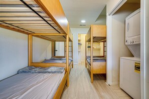 A dormitory room with bunk beds, a kitchenette, and a laundry area.