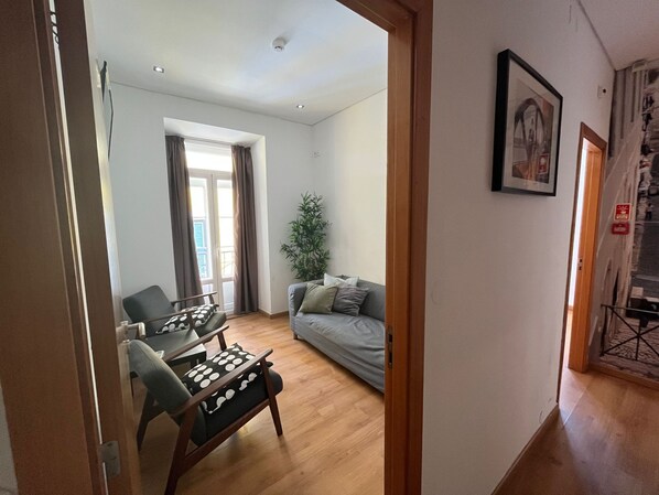 Un salon avec un canapé, une table à manger et des chaises, une plante en pot et un tableau accroché au mur.