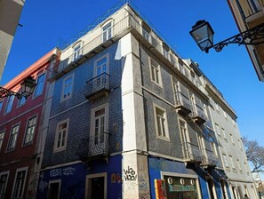 Un immeuble à plusieurs étages, doté d’une façade bleue, de balcons et d’une devanture visible avec une enseigne.