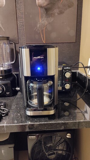 Une machine à café dotée d’un écran numérique et de boutons de commande, posée sur un plan de travail de cuisine.