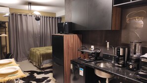 A compact kitchen with a refrigerator, microwave, coffee maker, and a sink.