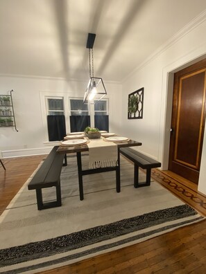 A dining area with a wooden table, benches, and a hanging light fixture.