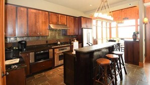 Una cocina con armarios de madera, una isla central con taburetes, un refrigerador y una estufa.