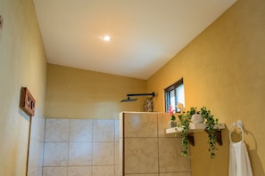 A bathroom with beige tiles, a window, a towel rack, and a potted plant.