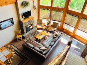 A cozy living room with a stone fireplace, a large sofa, and a television.