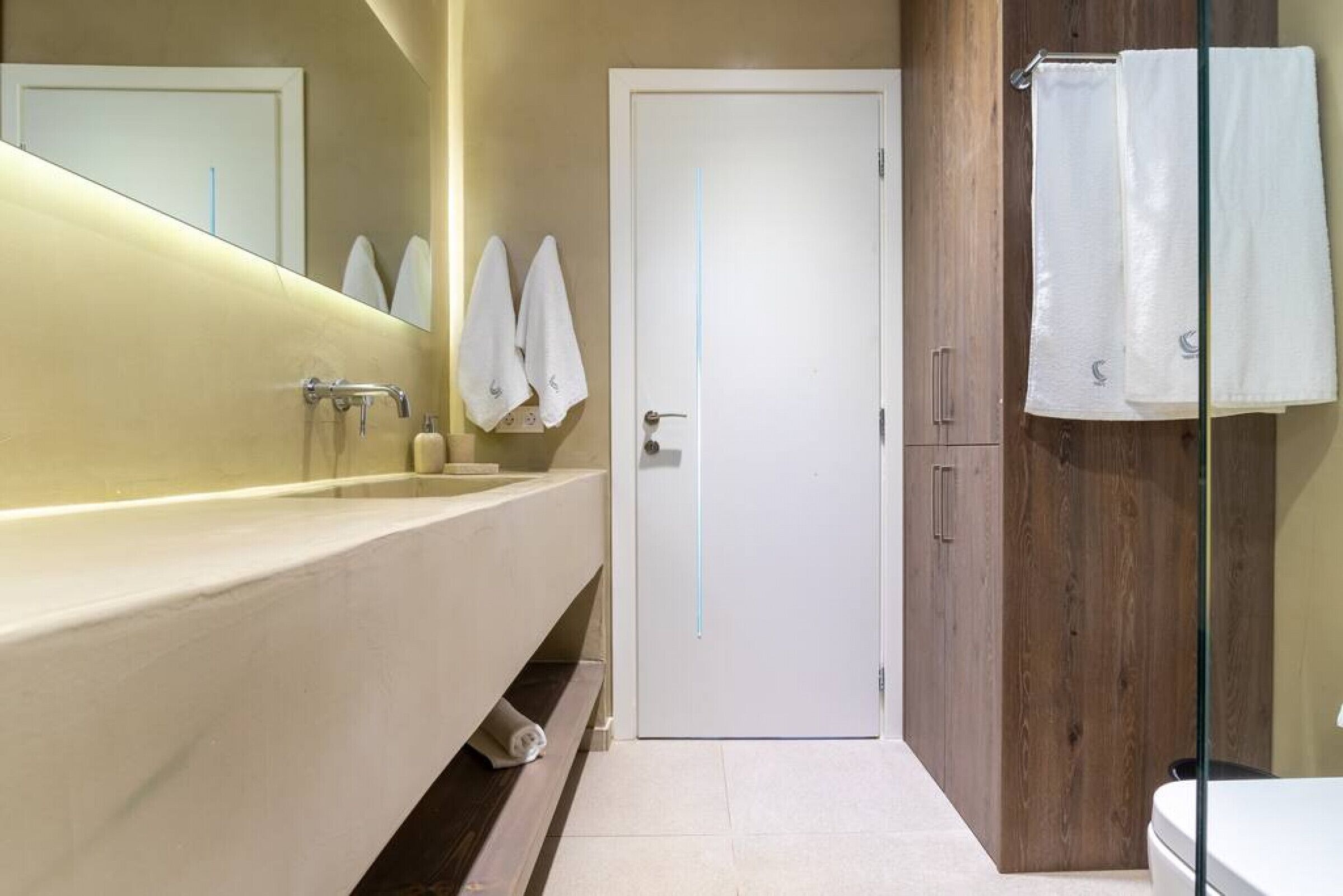 A modern bathroom with a large sink, a mirror, and a wooden cabinet.