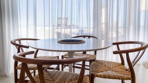 A round glass table with woven chairs, set against a sheer white curtain backdrop. - Wave an Idyllic Seafront Suite (Hersonissos)