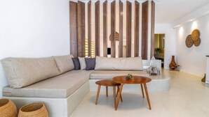 A modern living room with a sectional sofa, two wooden tables, and decorative items. - Wave an Idyllic Seafront Suite (Hersonissos)