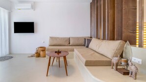 A modern living room with a beige sofa, a small wooden table, and decorative elephant figurines. - Wave an Idyllic Seafront Suite (Hersonissos)