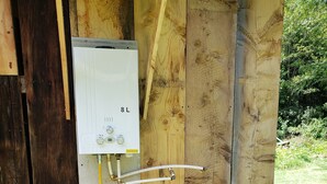 A propane exchange tank mounted on a wooden structure with a white electrical box and a yellow hose connected to it.