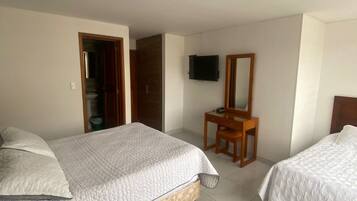 Habitación de hotel con dos camas, un escritorio de madera, televisor y armario.