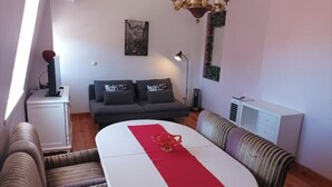 Een gezellige woonkamer met een bank, een eettafel met een rode loper en een kroonluchter.