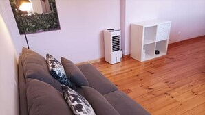 Een kamer met een bruine bank tegen een muur, een wit kastje en een houten vloer.