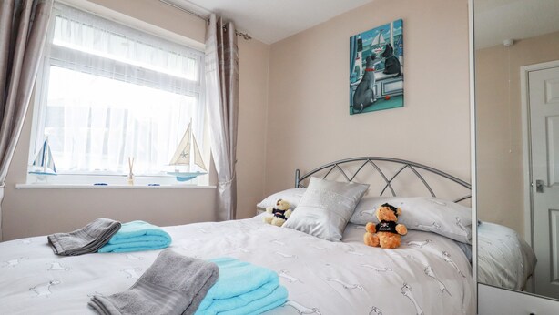 Ein Schlafzimmer mit Bett, Kissen, einem Teddybären, einem Segelboot und einem Bild an der Wand.