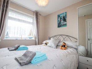 A bedroom with a bed, pillows, a teddy bear, a sailboat, and a painting on the wall. - Smugglers (Liskeard)
