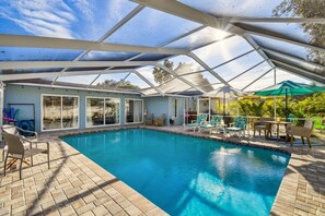 A covered swimming pool with lounge chairs and a patio area.