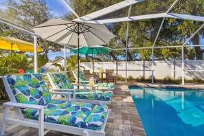 Zona de piscina con sillones de descanso y sombrillas.