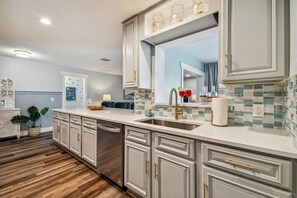 A modern kitchen with white cabinetry, a large island, and a tiled backsplash. - Tropical Pool Retreat in Tarpon Springs (Tarpon Springs)