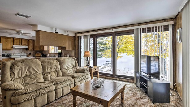 A living room with a beige sofa, a wooden coffee table, and a television on a stand. - Lakefront Eagle River Cottage w/ Private Dock (Eagle River)