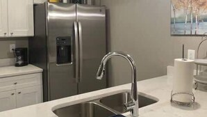 Una cocina moderna con electrodomésticos de acero inoxidable, un lavamanos doble y una encimera de mármol.