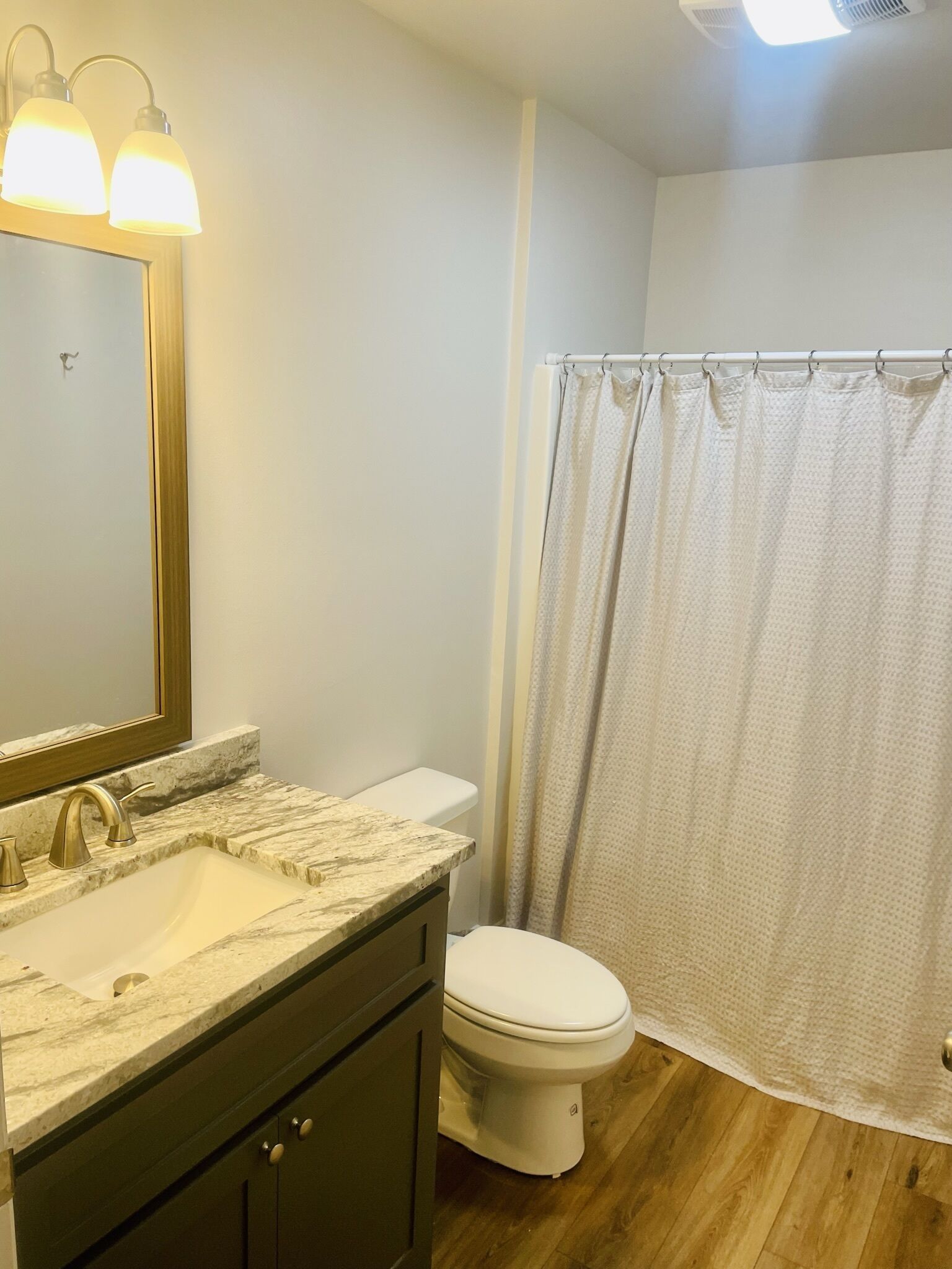 Une salle de bain avec un lavabo en marbre, des toilettes et un rideau de douche.