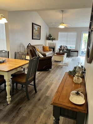 A dining area with a wooden table and chairs, a sofa, and a fireplace. - Budget-friendly, family-oriented home. Minutes from Main Attractions! (Sevierville)