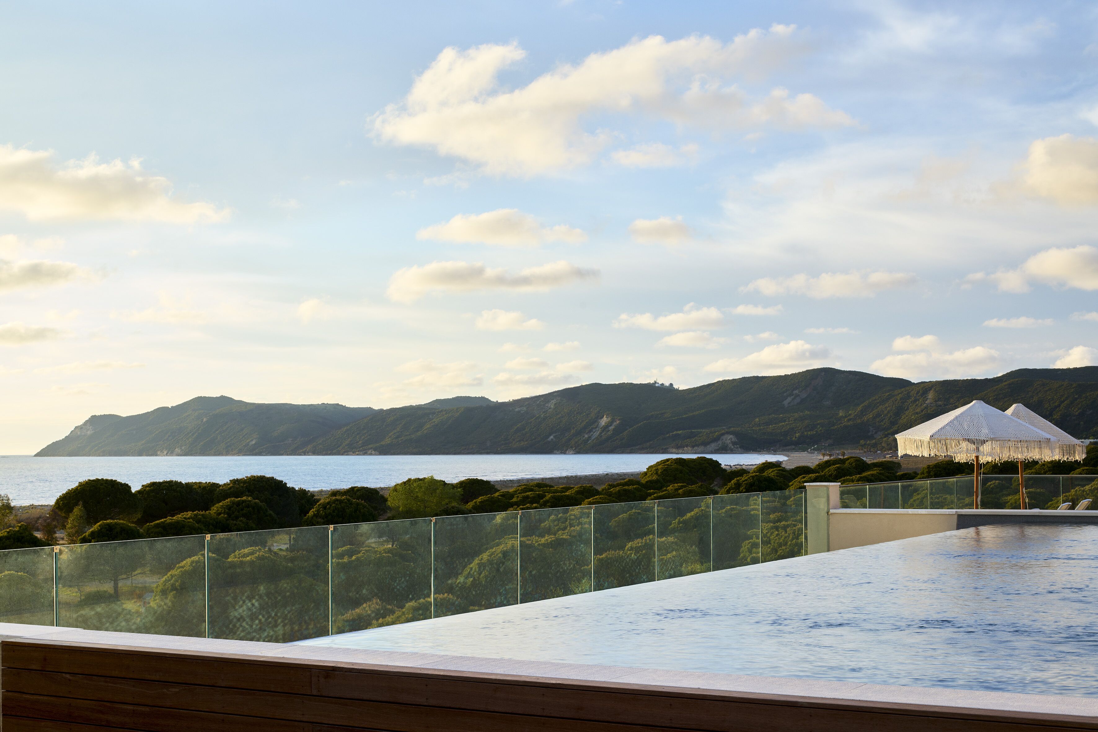 A rooftop infinity pool with a view of the sea and mountains.