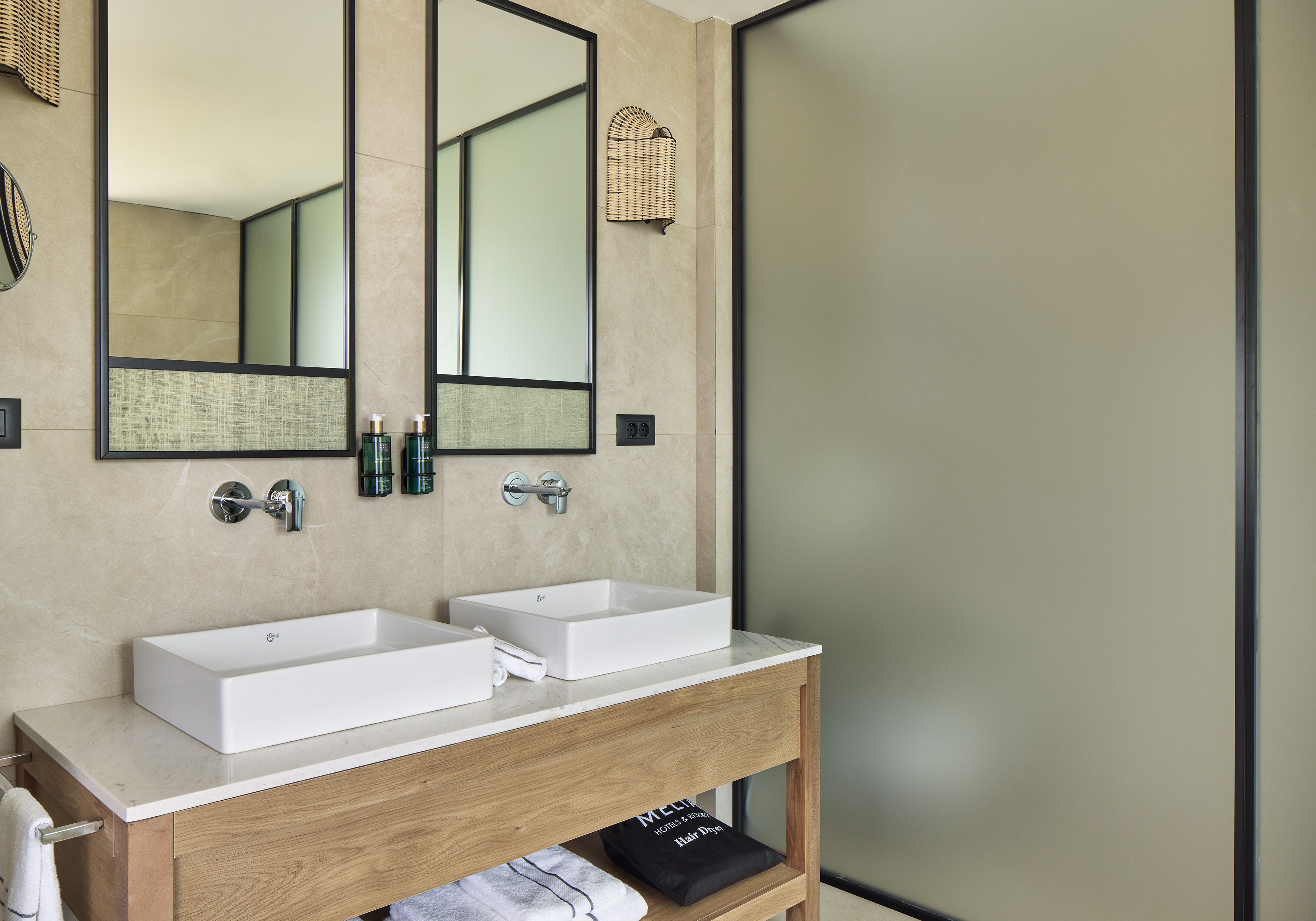 A modern bathroom with two sinks, a large mirror, and a wooden vanity.