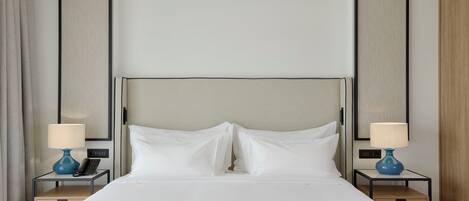 Hotellihuone, jossa on suuri sänky, kaksi yöpöytää valaisimineen, puhelin ja puinen yöpöytä.