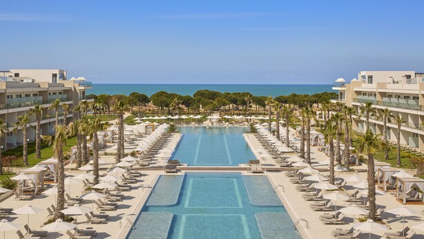 A resort with a central swimming pool, palm trees, and a view of the sea. - Melia Durres Albania (Ishëm)