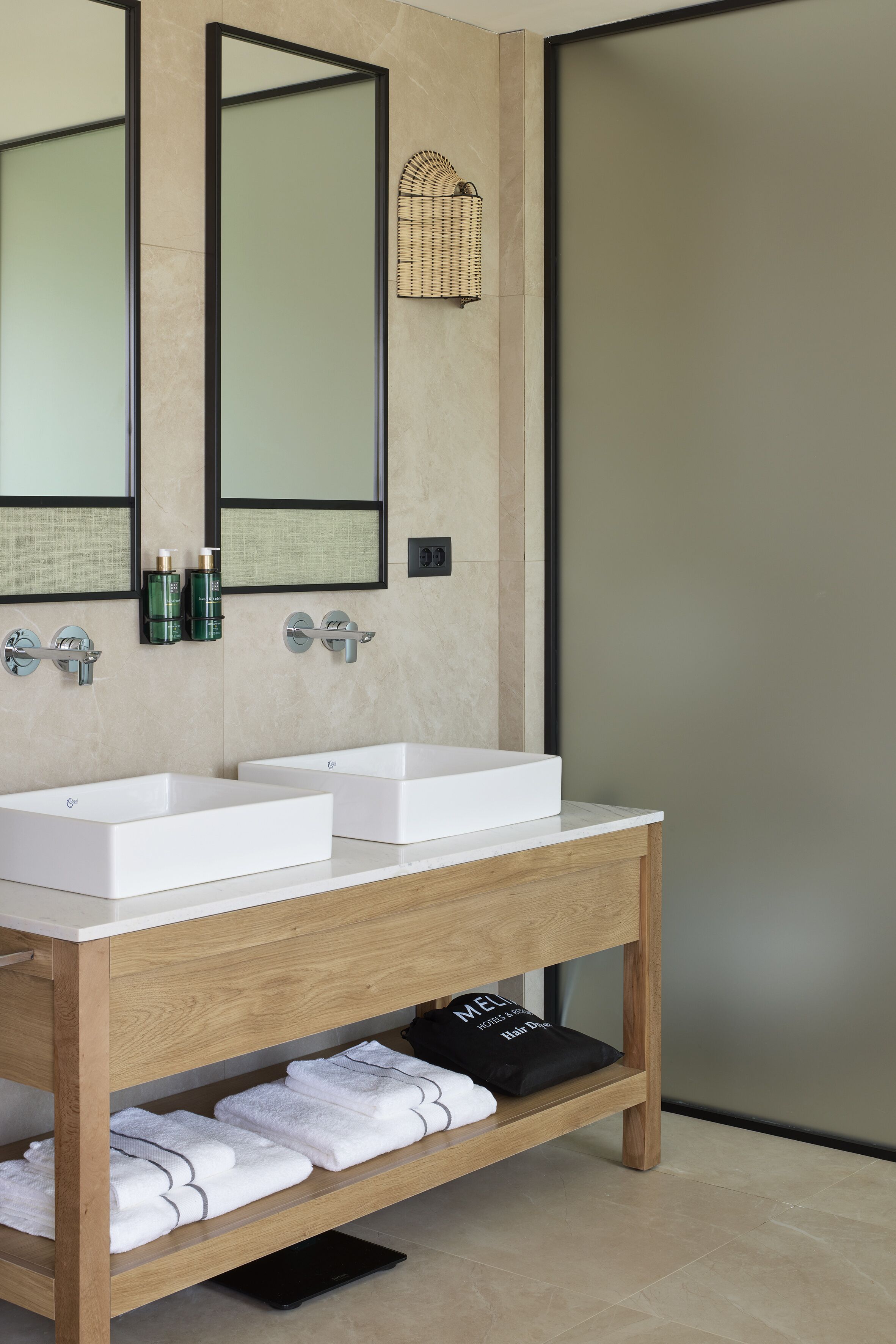 Un baño moderno con dos lavamanos blancos, un mueble de tocador de madera y un espejo grande.