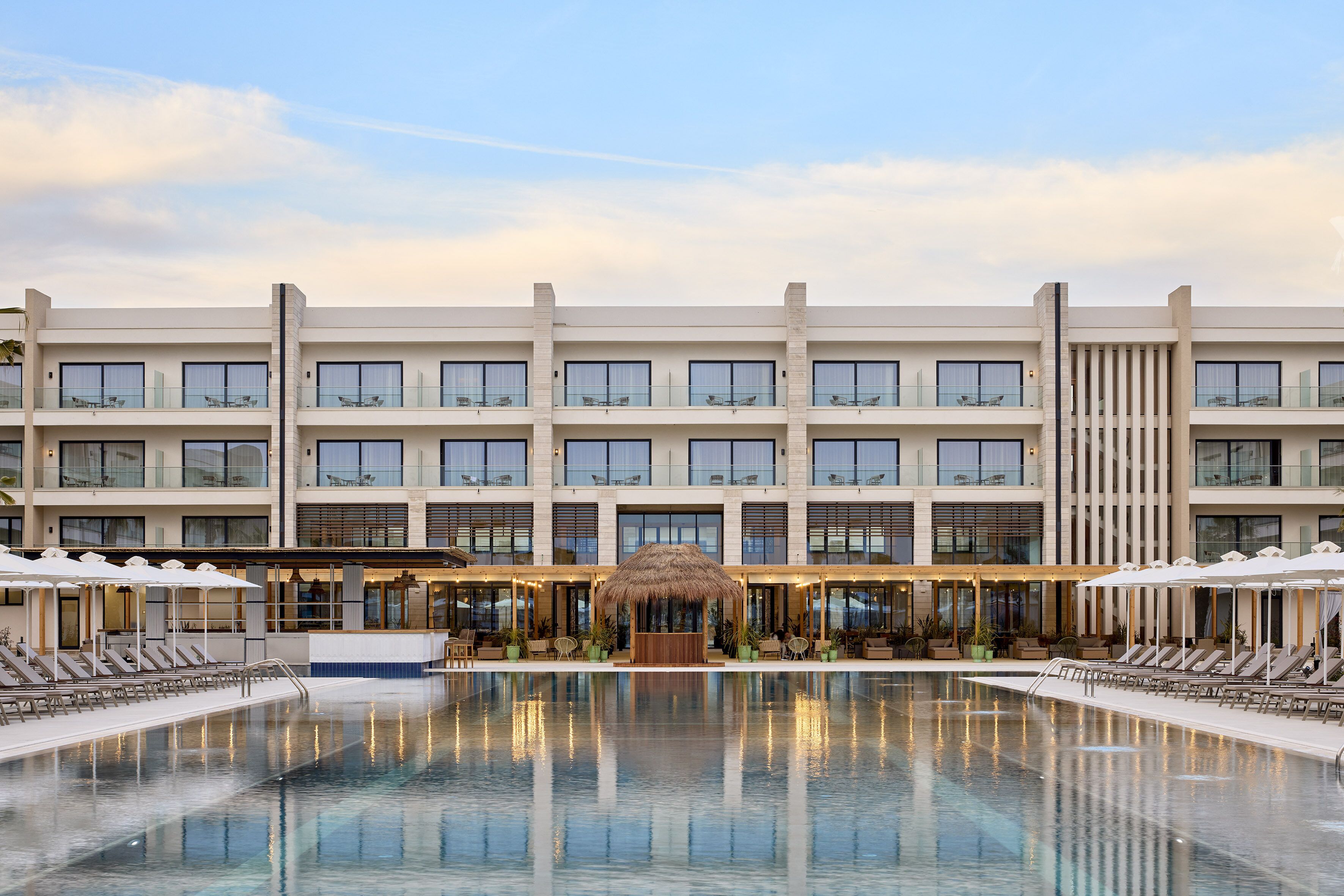 A hotel with a large pool, multiple balconies, and outdoor seating areas.