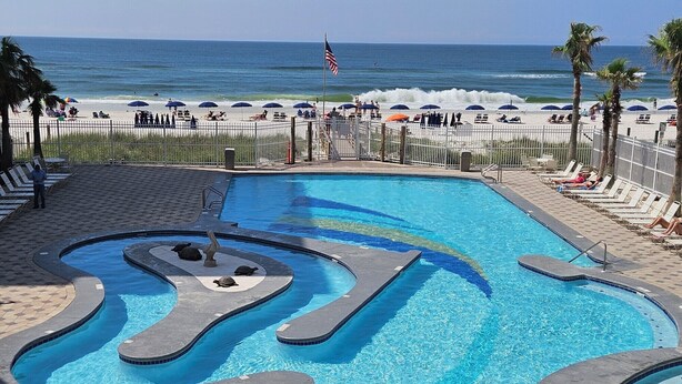 Une piscine au design original, entourée de parasols de plage et offrant une vue sur l’océan.