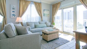 Un salon avec un canapé, une table basse et une vue sur la ville grâce à de grandes fenêtres.