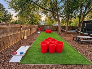 Un giardino sul retro con erba sintetica, una recinzione in legno e un trampolino.