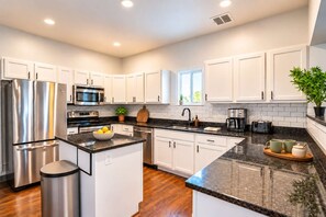 A modern kitchen with white cabinets, stainless steel appliances, and a granite countertop.