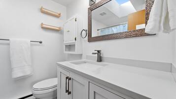 A modern bathroom with a white sink, a mirror with a decorative frame, and a toilet.