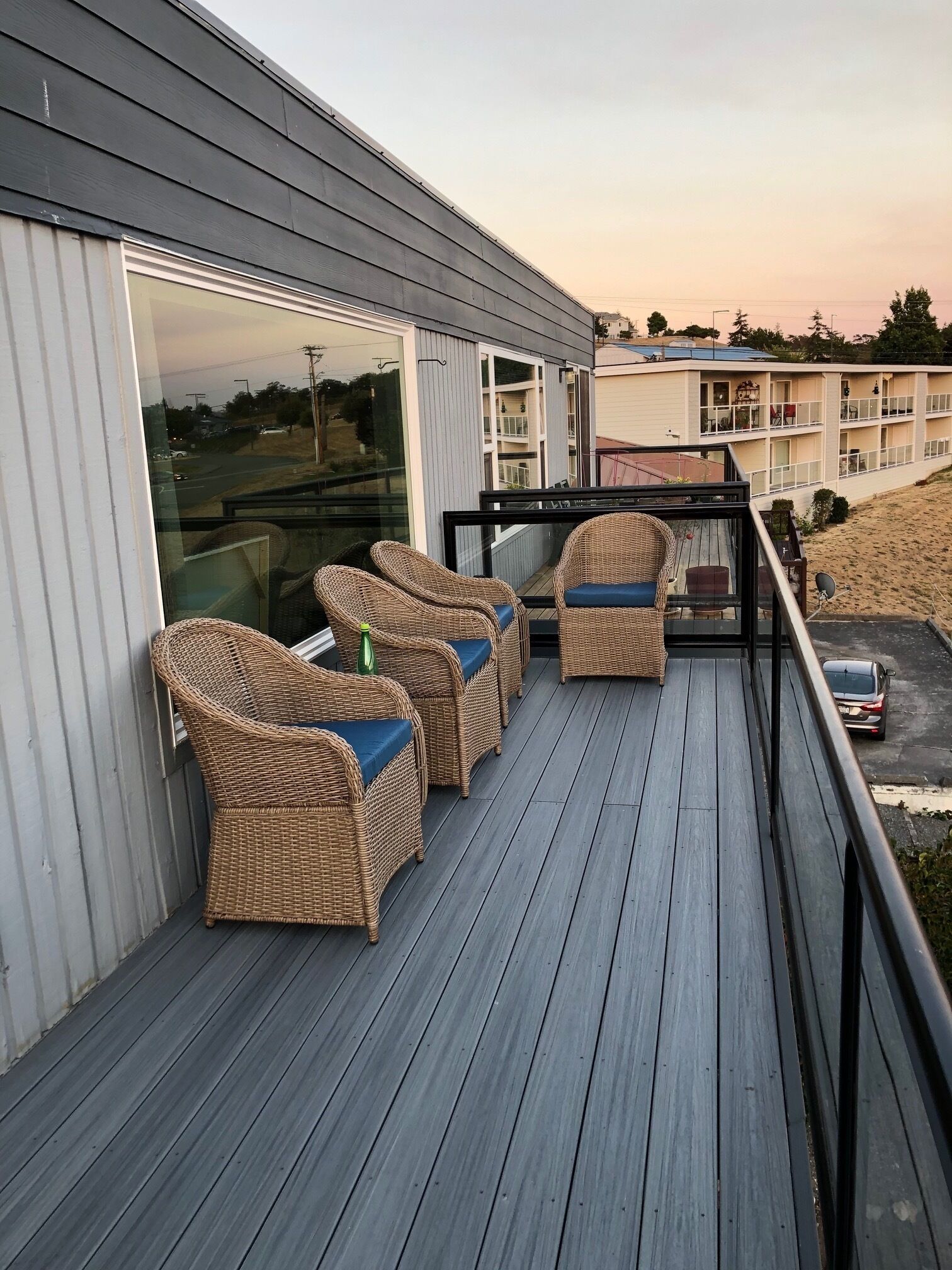 A deck with wicker furniture and a glass door leading to a balcony.