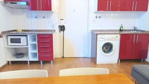 Eine kleine Küche mit Mikrowelle, roten Schränken und einer Waschmaschine.