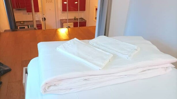Ein Hotelzimmer mit einem Bett, Holzboden und roten Schränken im Hintergrund.