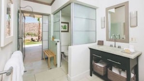 A modern bathroom with a glass shower enclosure, a white vanity, and a large mirror.