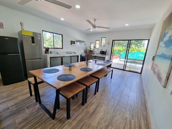 A modern kitchen with a wooden dining table, built-in appliances, and a view of the outdoor area.