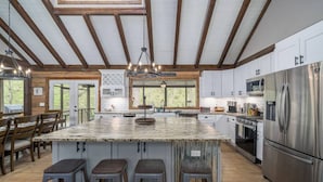 A spacious kitchen with a large island, stainless steel appliances, and wooden beams on the ceiling. - The Grande Lodge- Riverfront, Fiber, HotTub, Fish, DogOK, Game Room, Movie Room (Ellijay)
