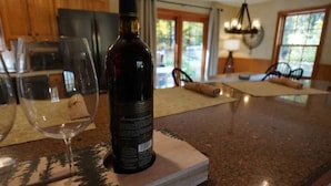 A kitchen counter with a wine bottle and a wine glass. - Woodlands Retreat (Lake George)