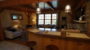 A cozy kitchen with wooden cabinets, a bar area, and a seating area with a sofa and chairs. - Woodlands Retreat (Lake George)