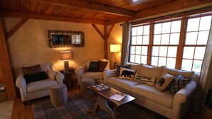 A cozy living room with two sofas, a coffee table, and a fireplace. - Woodlands Retreat (Lake George)