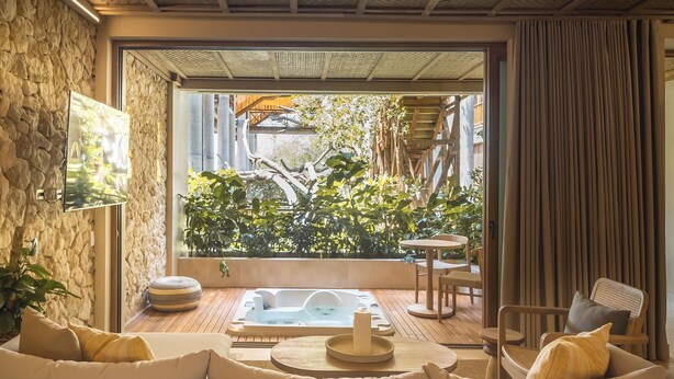 A spa area with a hot tub, seating, and a view of greenery. - Hotel Aimarawa (San Antero)