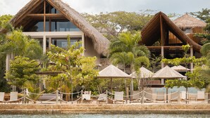 A resort with thatched-roof villas, a pool area with lounge chairs, and tropical vegetation. - Hotel Aimarawa (San Antero)