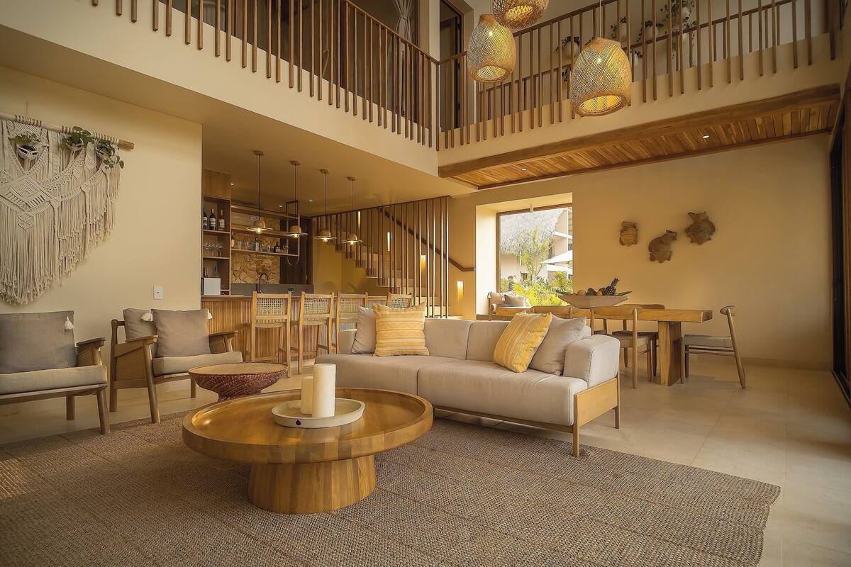 A spacious living area with a high ceiling, a staircase, and a dining area.